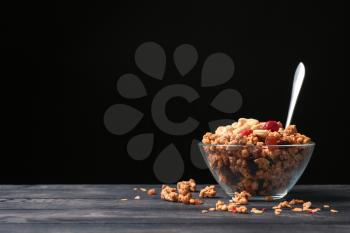 Granola with dried fruits and nuts in glass bowl on dark wooden table�