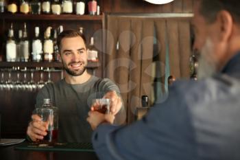 Young barman serving client in pub�
