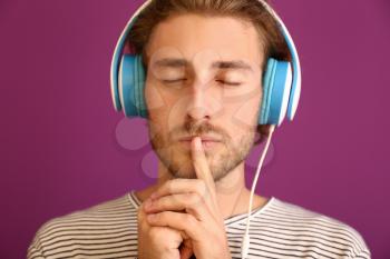 Young man listening to music on color background�
