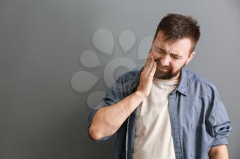 Man suffering from toothache on grey background�
