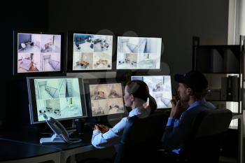 Security guards monitoring modern CCTV cameras in surveillance room�