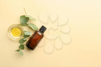 Bottle and bowl with eucalyptus essential oil on color background�