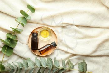 Bowl and bottles of eucalyptus essential oil on light cloth�