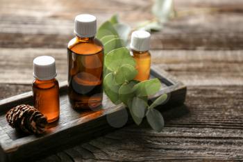 Bottles of eucalyptus essential oil on wooden background�