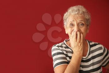 Portrait of elderly woman after making mistake on color background�