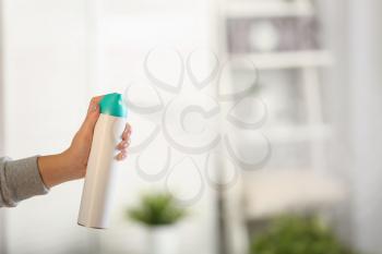 Woman spraying air freshener at home�