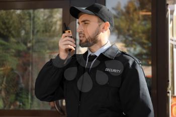 Male security guard with portable radio transmitter outdoors�