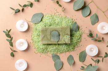 Burning candles with eucalyptus leaves, sea salt and soap bar on color background�