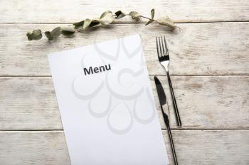 Blank menu with cutlery on wooden table�
