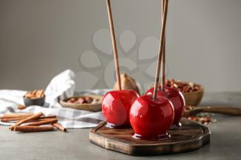 Wooden board with delicious candy apples on table�