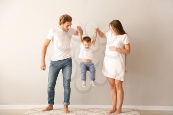 Happy family playing near white wall�