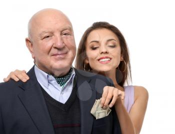 Young woman taking money from senior man's pocket on white background. Marriage of convenience�