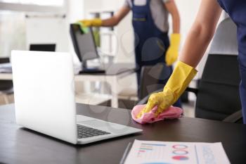 Janitor wiping table in office�