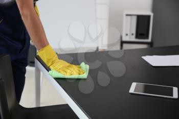 Janitor wiping table in office�