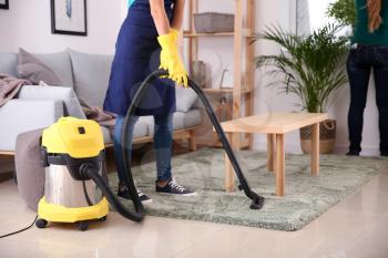 Female janitor hoovering carpet in flat�
