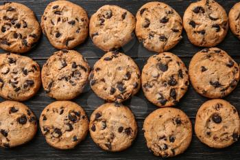 Tasty cookies with chocolate chips on dark wooden table�