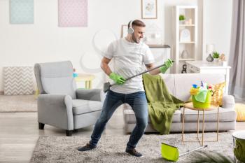 Young man having fun while cleaning his flat�