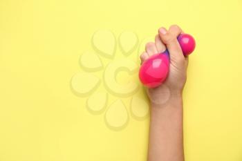 Female hand squeezing stress ball on color background�