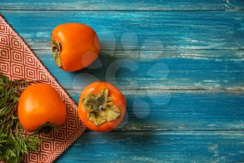 Tasty ripe persimmons on color wooden table�