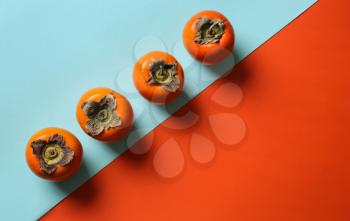 Tasty ripe persimmons on color background, top view�