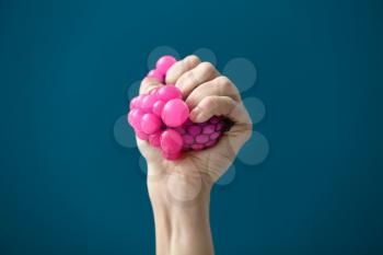 Female hand squeezing stress ball on color background�