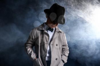 Cute little detective in smoke on dark background�