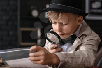 Cute little detective working with evidence at table�