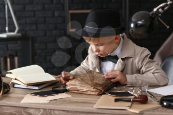 Cute little detective reading old book indoors�