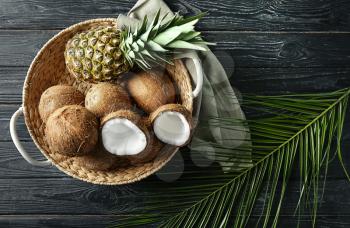 Basket with ripe coconuts and pineapple on wooden background�