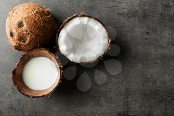 Ripe coconut and shell with milk on grey background�