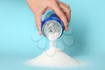Woman pouring sugar from can on color background�