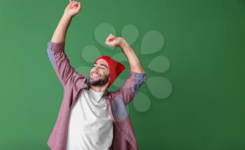 Handsome young man dancing on color background�
