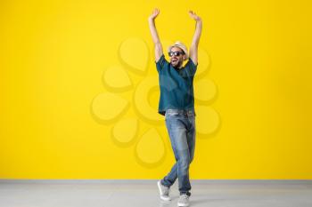 Handsome young man dancing near color wall�