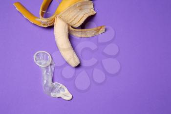 Banana and condom with white liquid on color background. Erotic concept�
