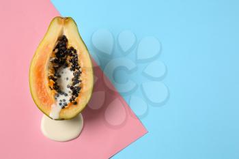 Half of papaya with dripping white liquid on color background. Erotic concept�