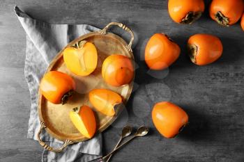 Tray with ripe persimmons on grey background, top view�