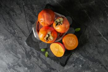 Plate with ripe persimmons on table, top view�