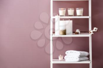 Many burning candles on shelves near color wall�