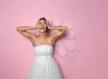Screaming young bride on color background�