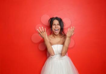 Screaming young bride on color background�