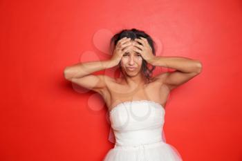 Stressed young bride on color background�