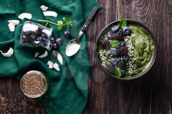 Tasty spirulina smoothie with berries in bowl on dark wooden table�