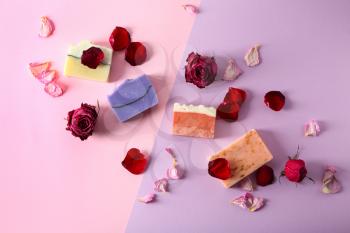 Handmade soap bars and flowers on color background, top view�