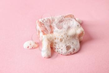 Handmade soap bar with foam on color background�
