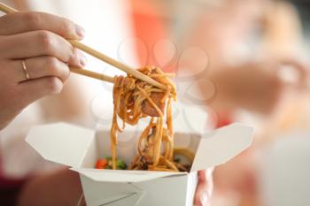 Woman eating chinese noodles from takeaway box, closeup�
