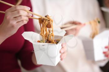 Woman eating chinese noodles from takeaway box, closeup�