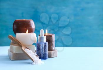 Spa composition with candles and cosmetic products on color background�