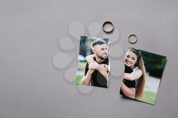 Torn photo of happy couple with rings on grey background. Concept of divorce�