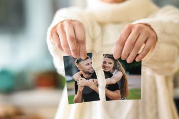 Woman tearing up photo of happy couple, closeup. Concept of divorce�