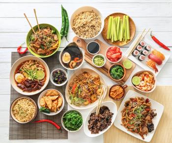 Assortment of Chinese food on white wooden table�